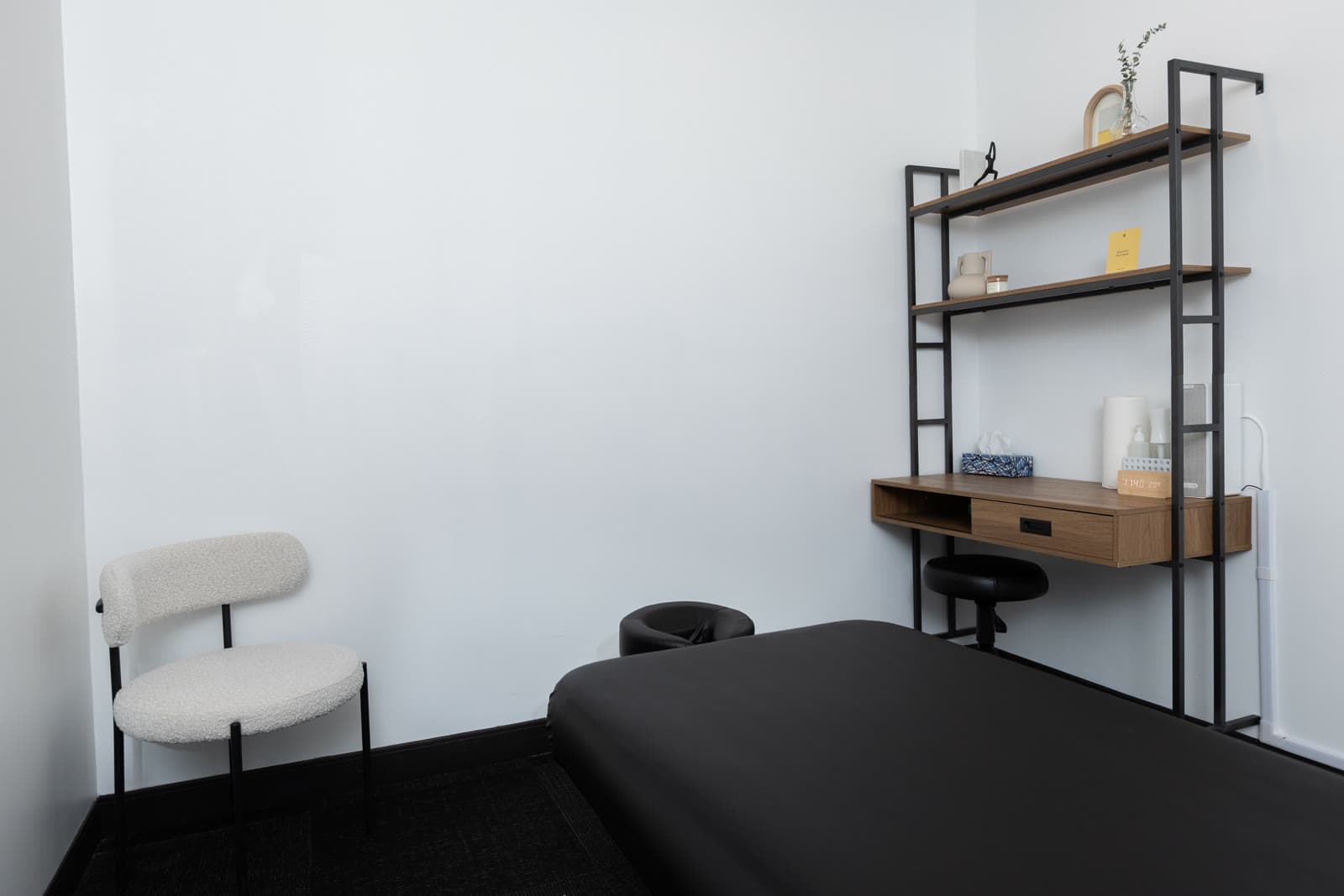 Minimalist private treatment room with a black therapy table