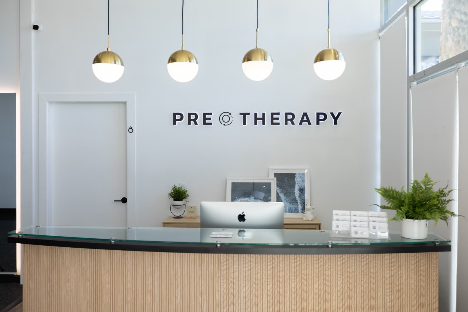 PRE Therapy reception desk with brass pendant lights and branded wall