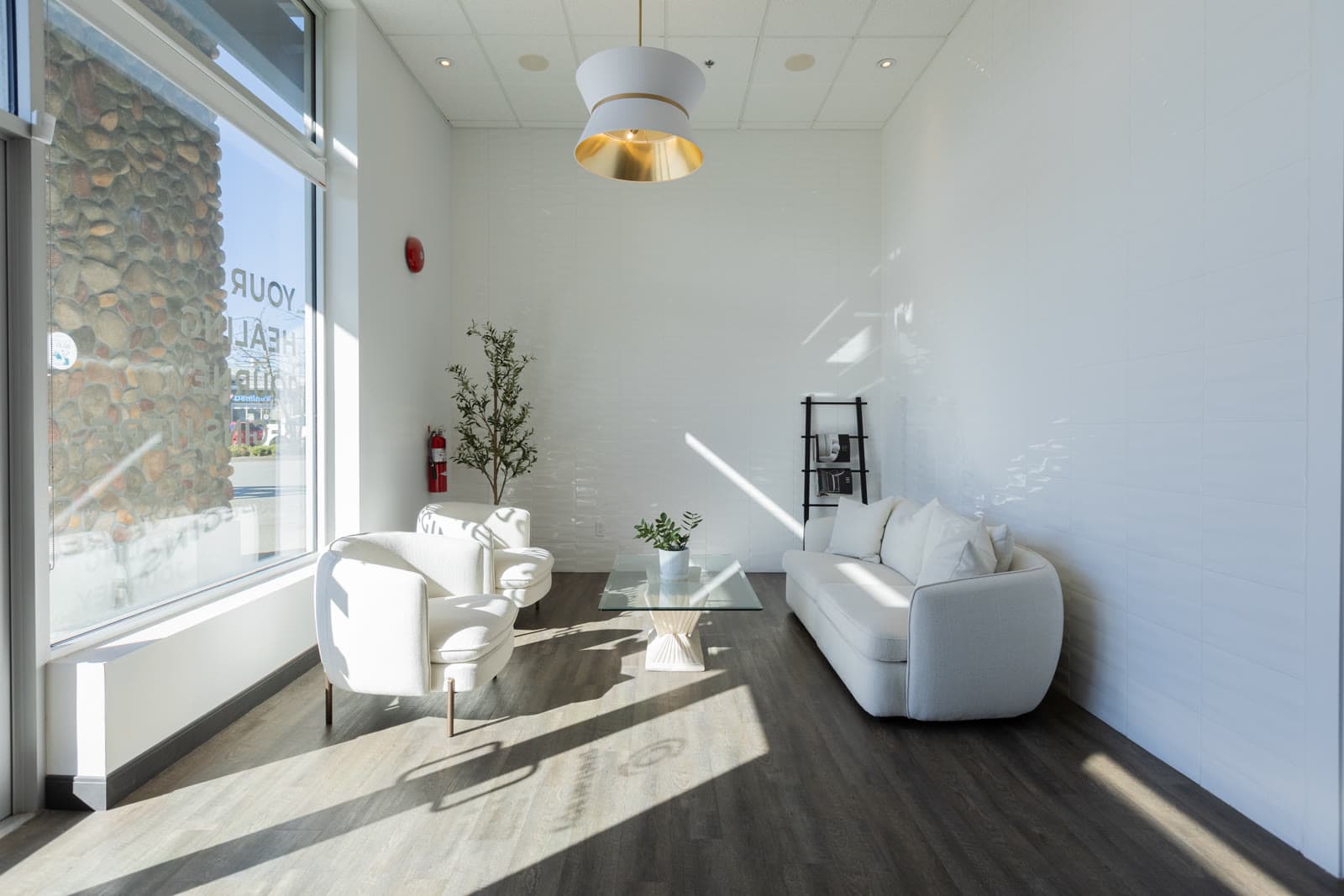 Sunlit waiting lounge with white armchairs at PRE Therapy
