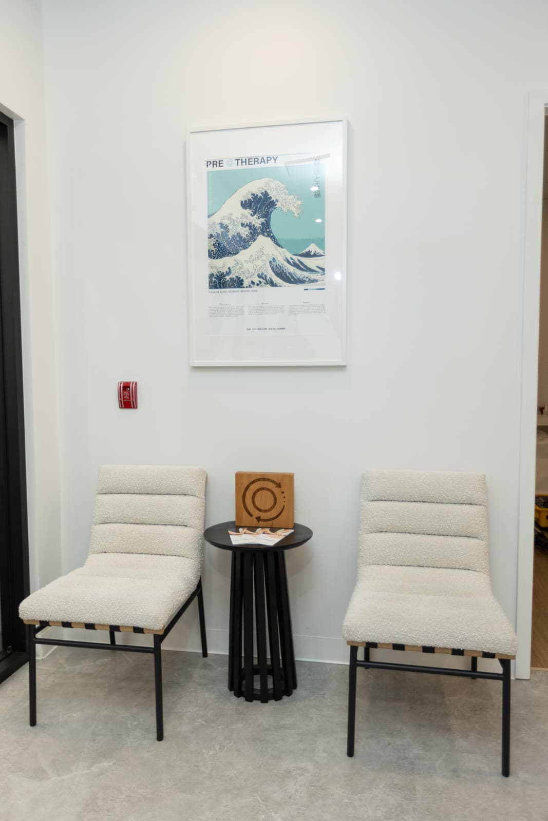 Reception nook with cream armchairs and a framed wave print