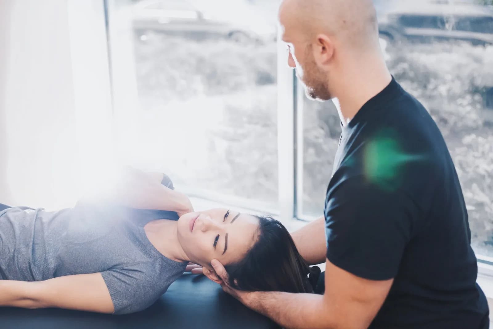 PRE Therapy practitioner providing hands-on neck treatment in a bright clinic room.